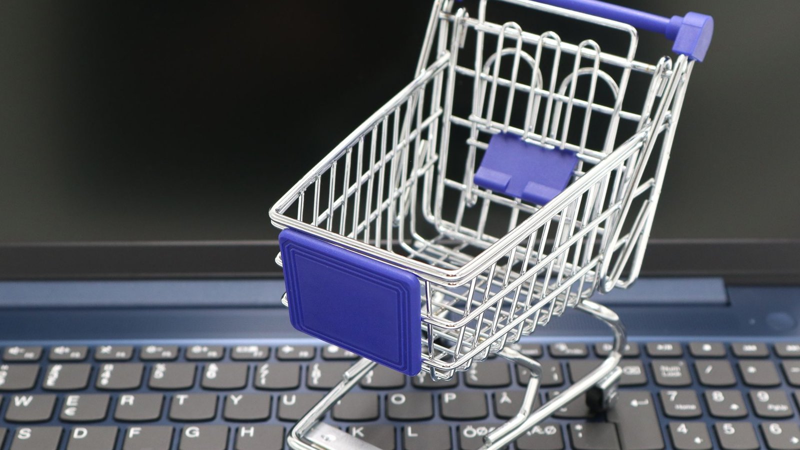 Mini carrinho de compras sobre teclado de laptop simbolizando loja virtual
