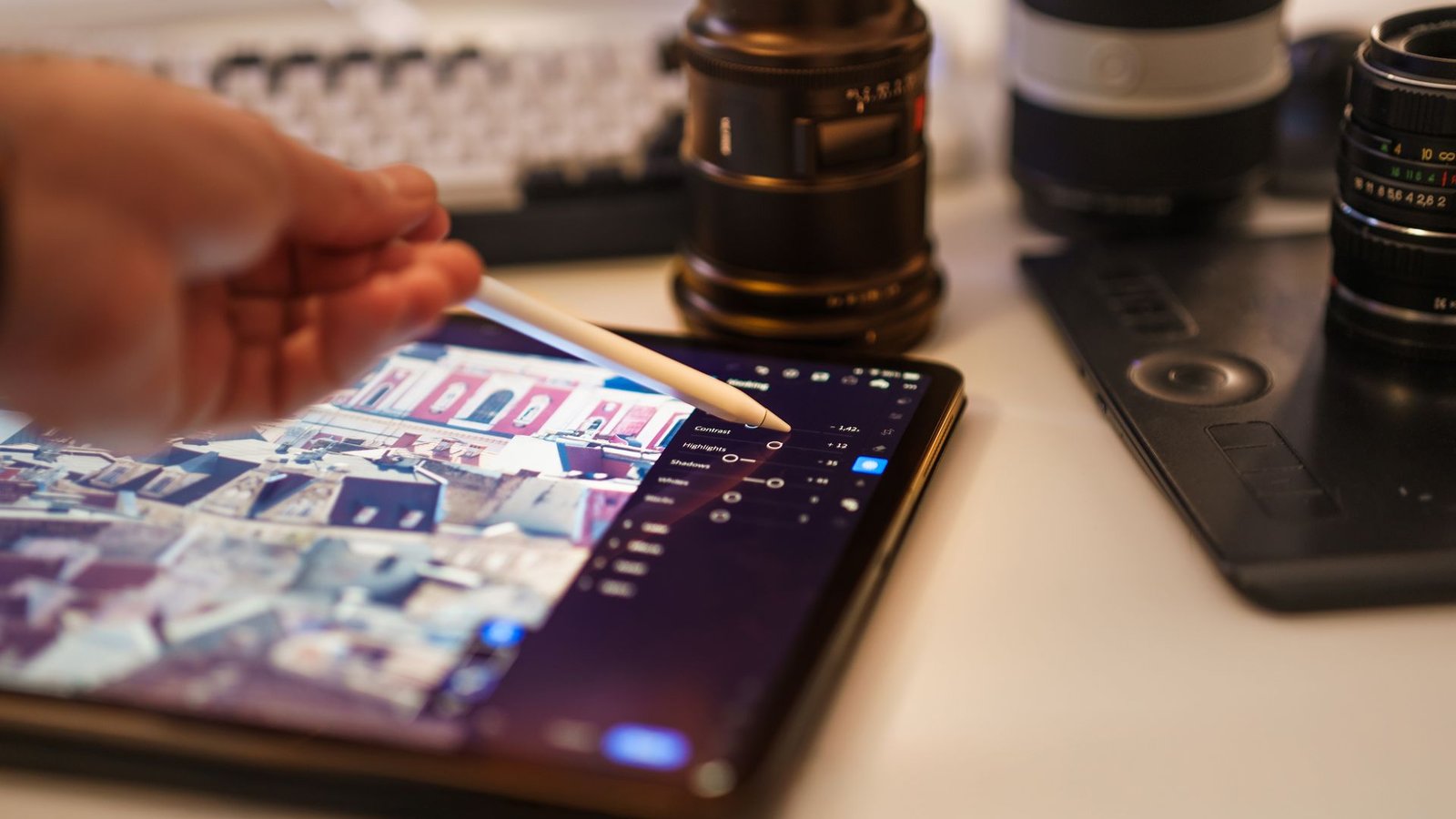 Mesa de trabalho com edição de fotos profissionais, tablet e lentes